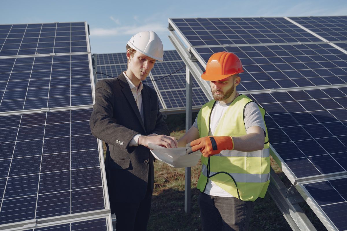 Two people reviewing information beside solar panels