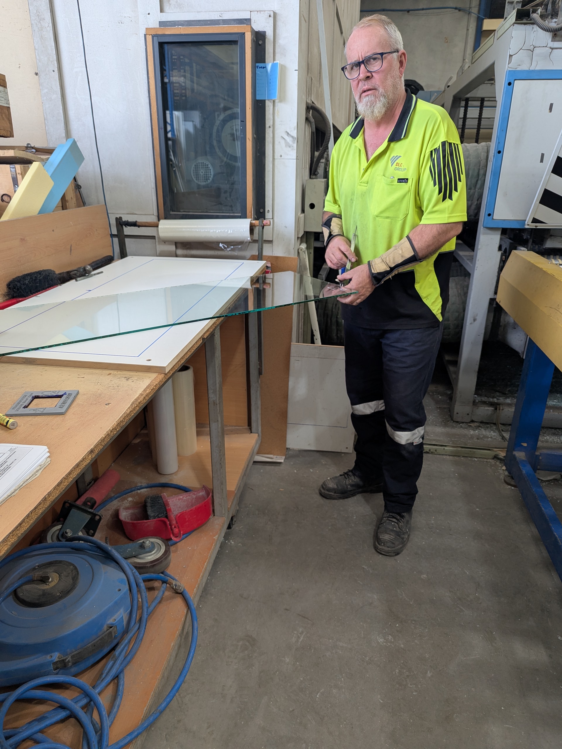 Worker handling a glass panel at a manufacturing workbench